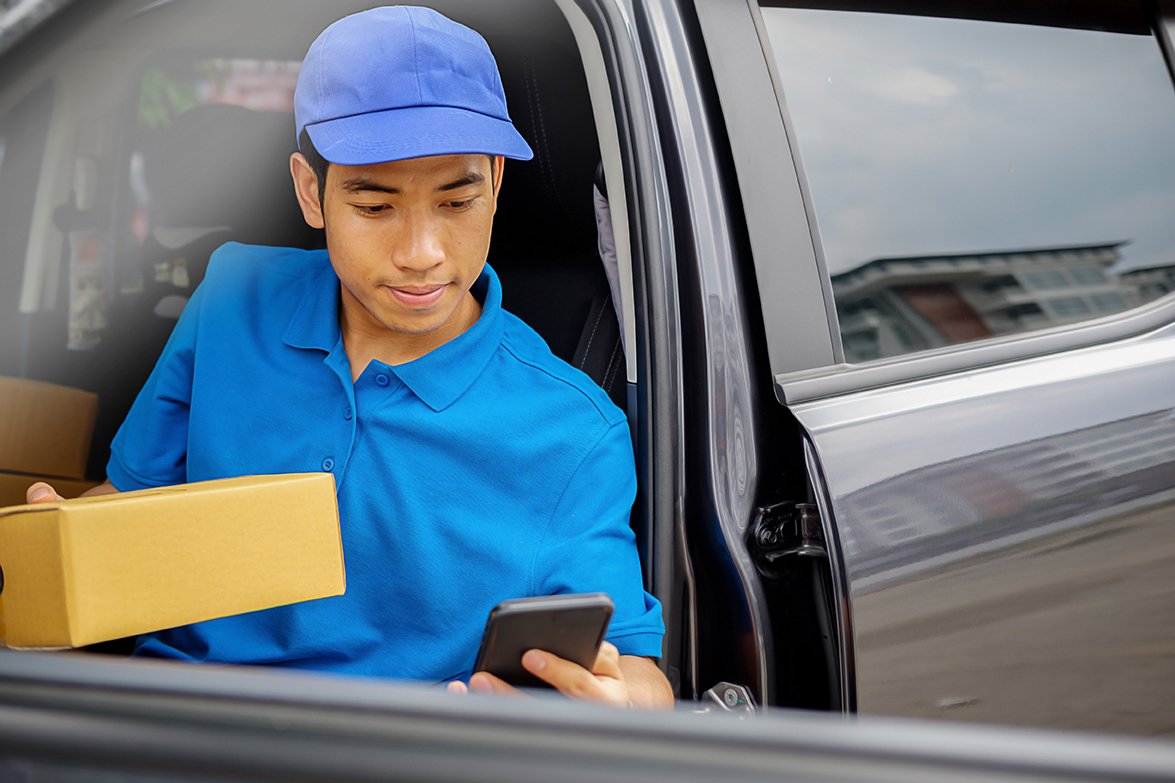 Delivery driver with Commercial drivers license driving van with parcels on seat outside warehouse in Rockland County