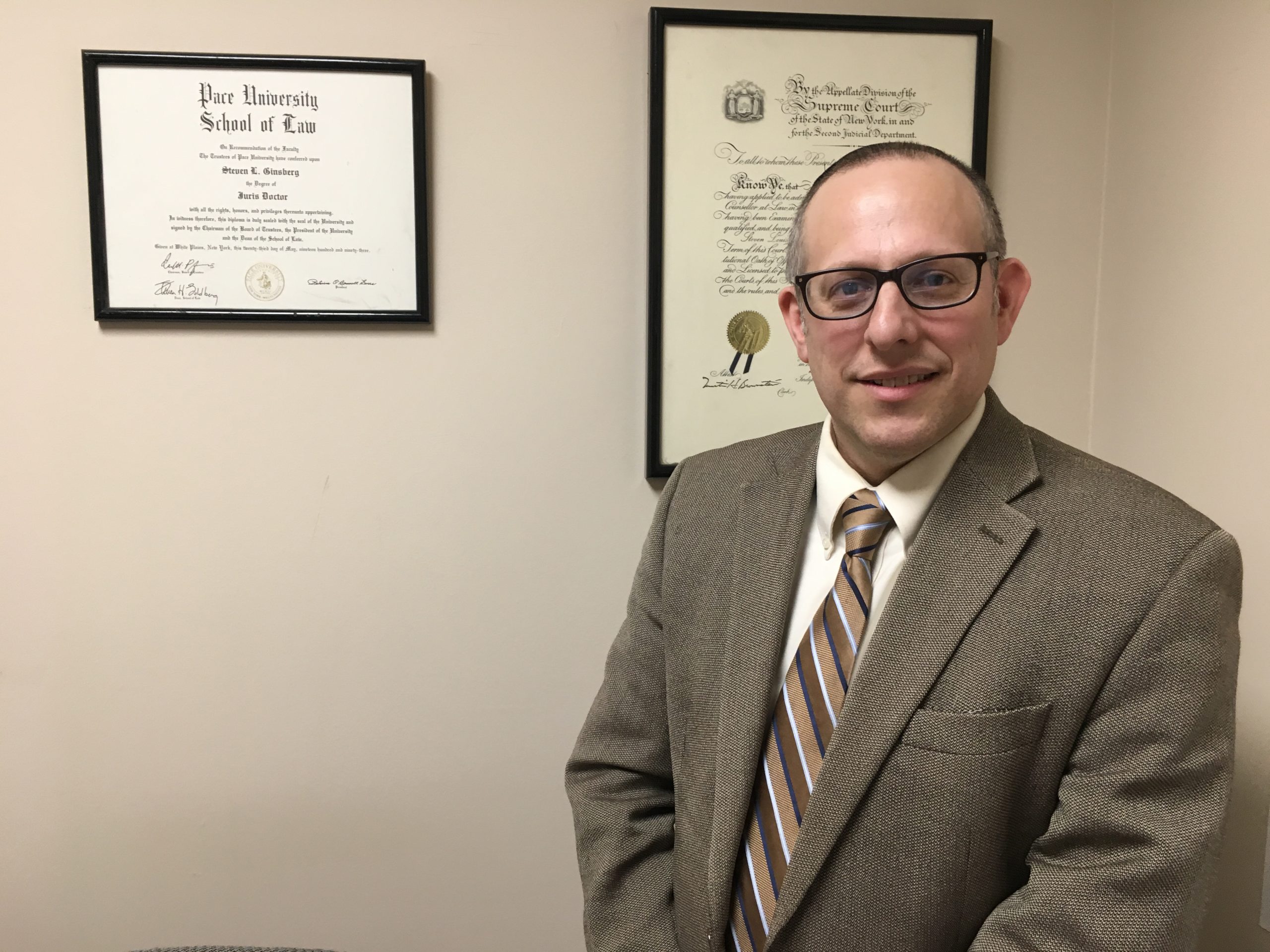 Traffic Attorney Steven L Ginsbergin front of law degree Traffic Lawyer Steven L Ginsberg in his Rockland County Office
